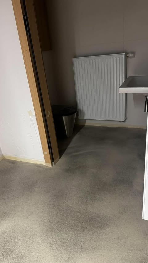 Narożnik wnętrza z białym grzejnikiem na szarej ścianie i betonową posadzką