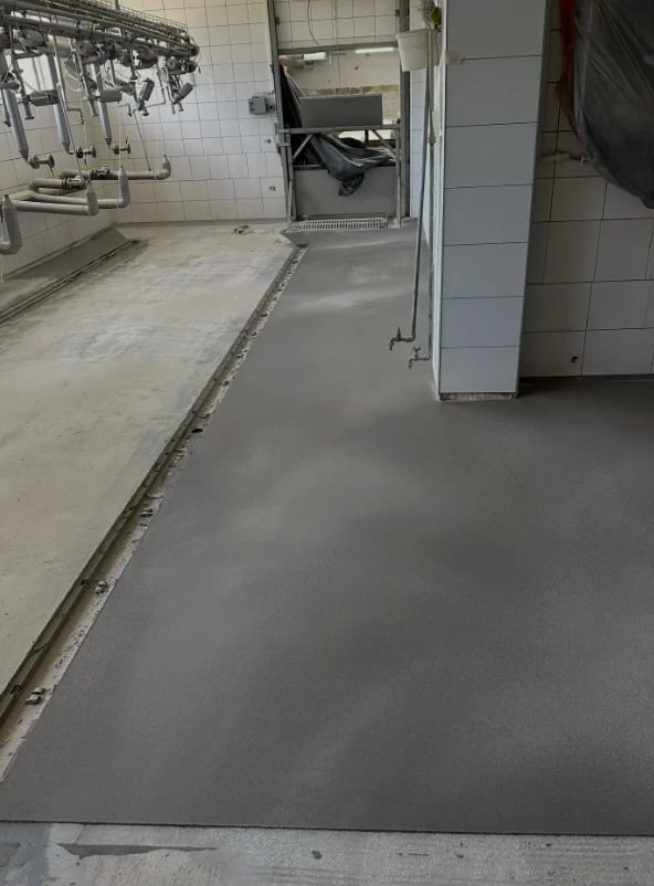 Zadaszony taras z niebieskimi drzwiami i posadzką z kruszywa