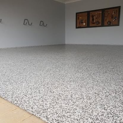 Garaż z szarą posadzką żywiczną w melanżu i narzędziami na ścianie